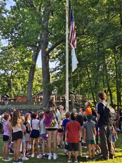 campers standing around flagpole while flag is being raised